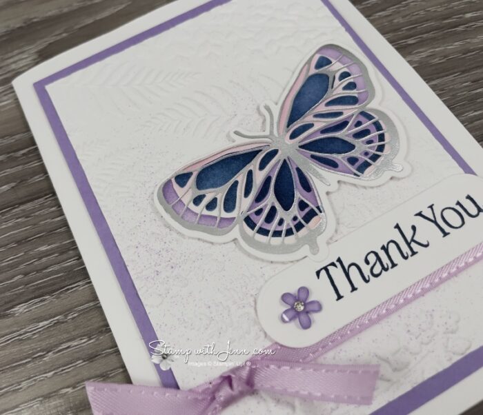 Close-up of a silver hot foiled butterfly coloured with Fresh Freesia and Highland Heather ink